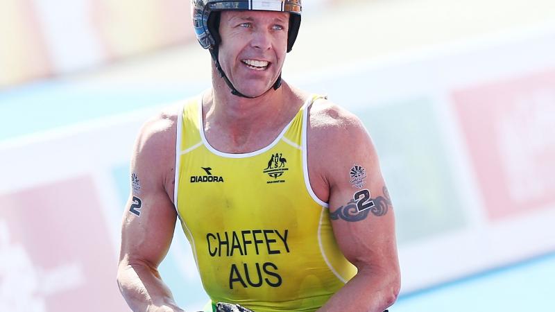 male Para triathlete Bill Chaffey smiles after crossing the finish line in his wheelchair