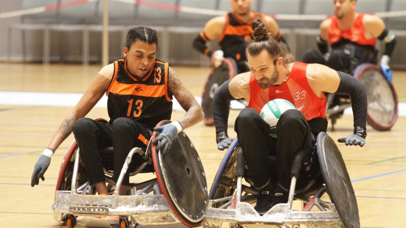 Two male wheelchair rugby players collide with their wheelchairs 