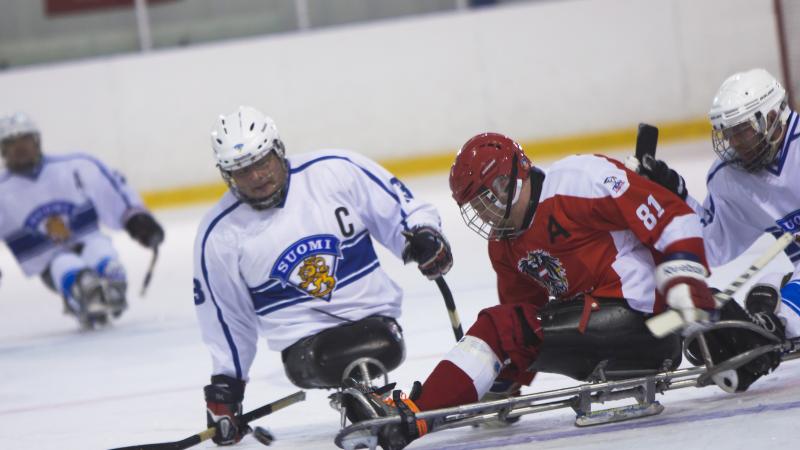 male Para ice hockey player Markku Hirvela defends the puck from a Polish player
