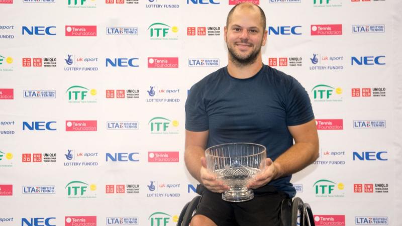 male wheelchair tennis player Stefan Olsson smiling and holding a crystal trophy