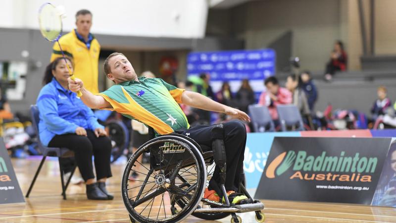 Male Australian badminton player in a wheelchair attempts to hit the birdie in the air