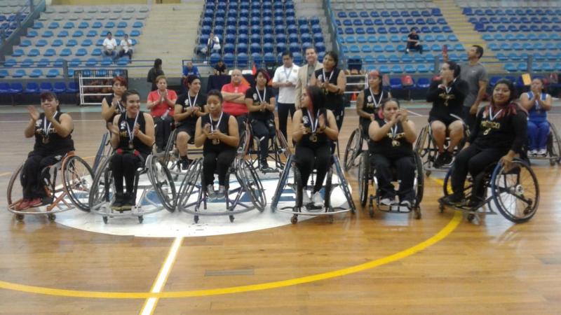 Female Mexican wheelchair basketball players pose after a victory