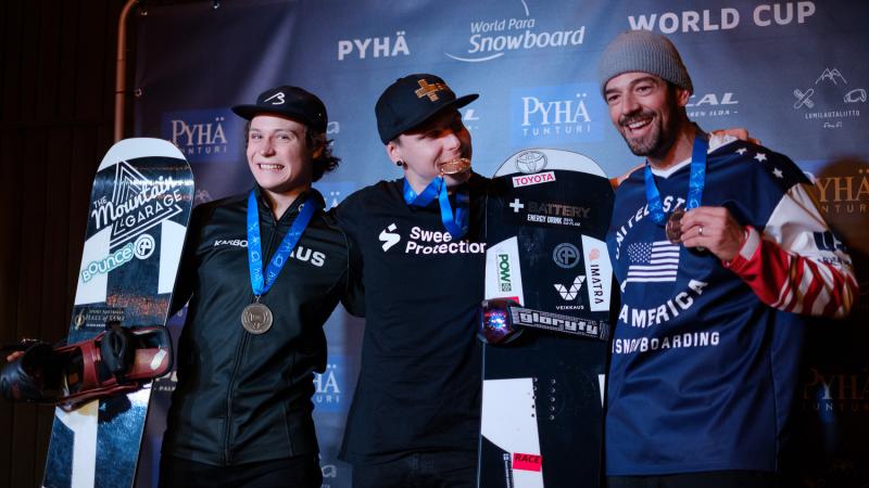 Three male snowboarders pose together with their medals