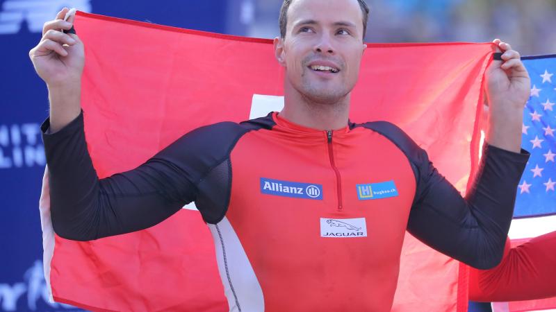 male wheelchair racer Marcel Hug holding up a Switzerland flag