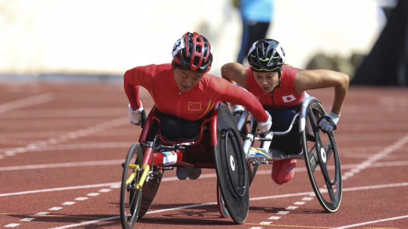 female wheelchair racer Hongzhuan Zhou rolls her wheels to stay ahead of a Japanese athlete