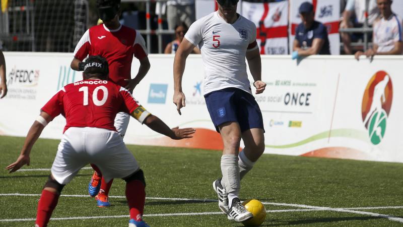 male blind footballer Dan English dribbles the ball past an opposition player