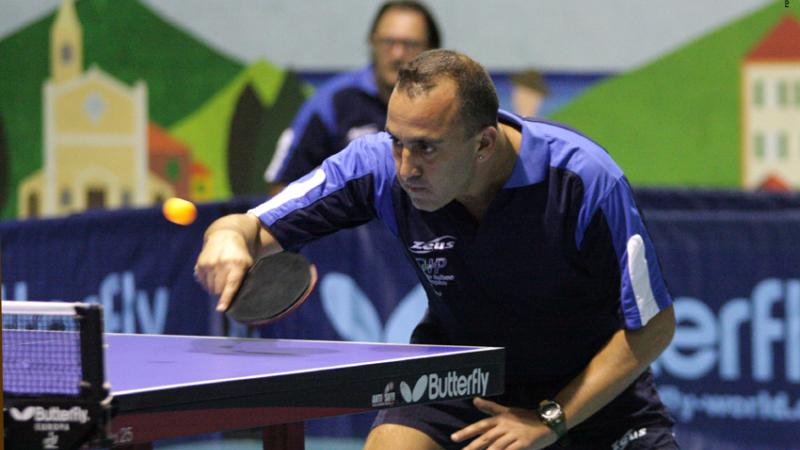 a male intellectually impaired table tennis player plays a backhand across the table