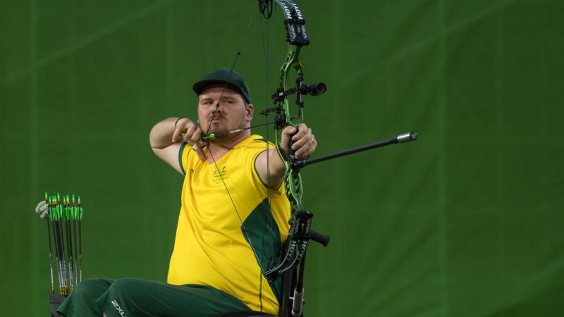 Australian male archer in wheelchair pulls back on his bow