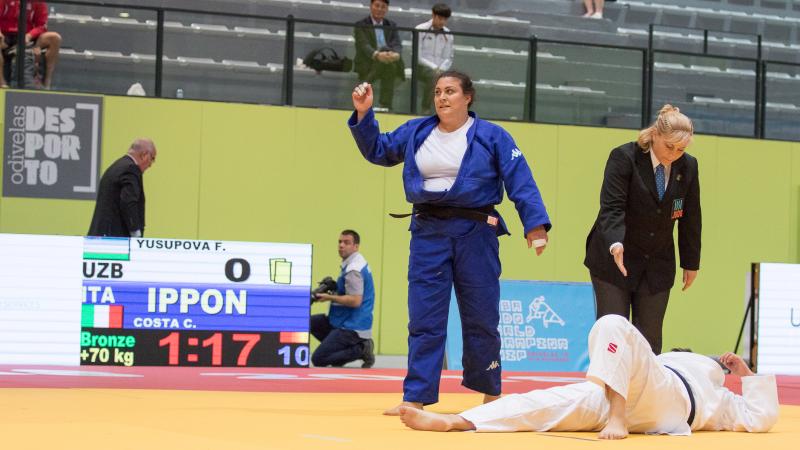 female judoka Carolina Costa stands over her opponent on the ground after winning the fight by ippon