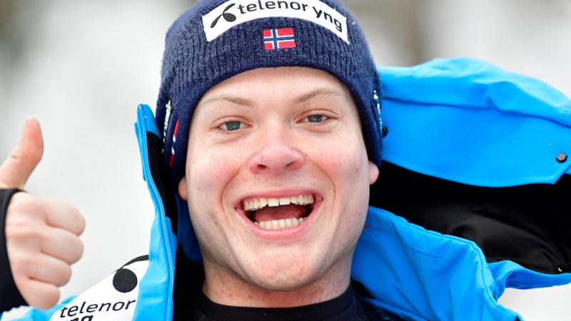 male Para alpine skier Jesper Pedersen smiles and gives a thumbs up to the camera