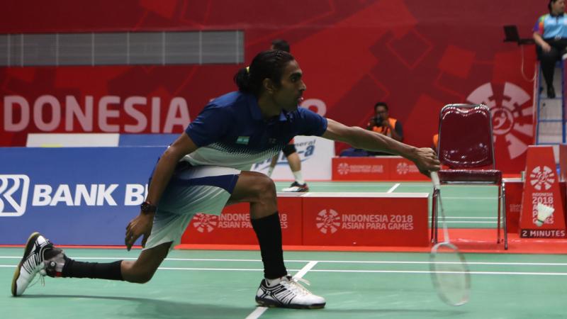 male Para badminton player Pramod Bhagat lunges to play a backhand