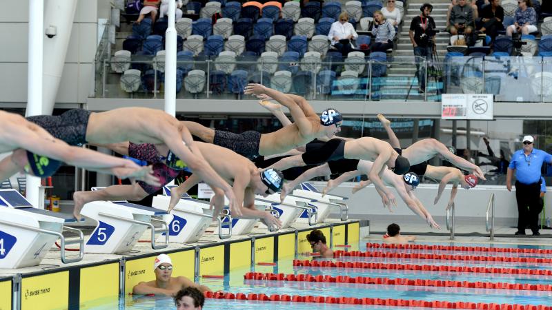 male Para swimmers diving into a pool at the start of the race in Melbourne