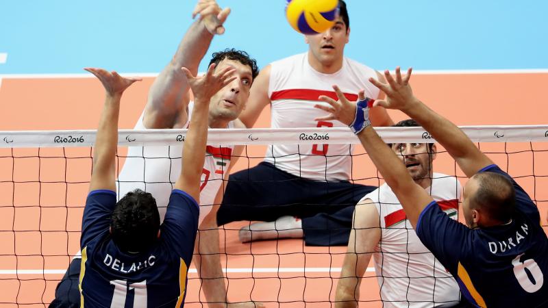 a group of male sitting volleyball players on court during a match