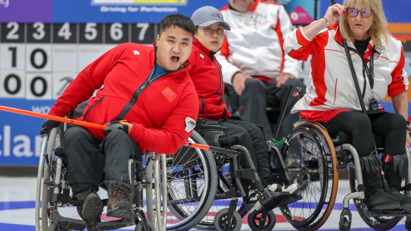 Chinese male wheelchair curler reacts as he releases his stone