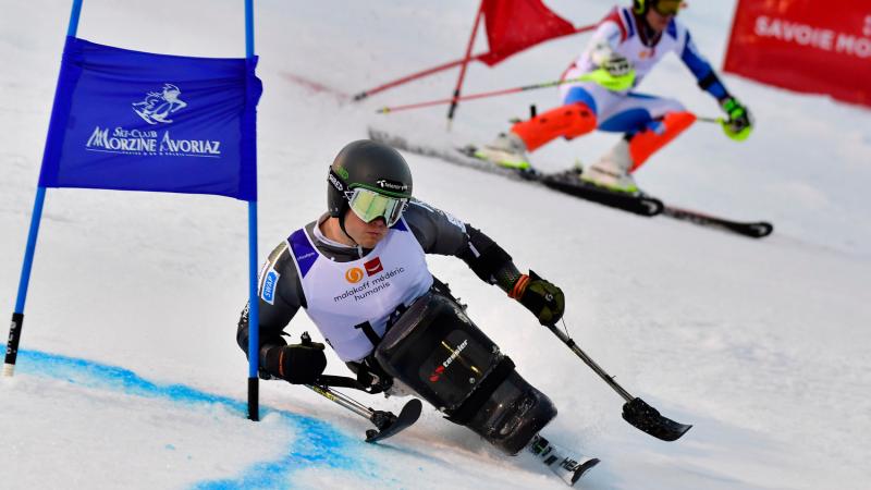 male sit skier Jesper Pedersen races head to head with a standing skier