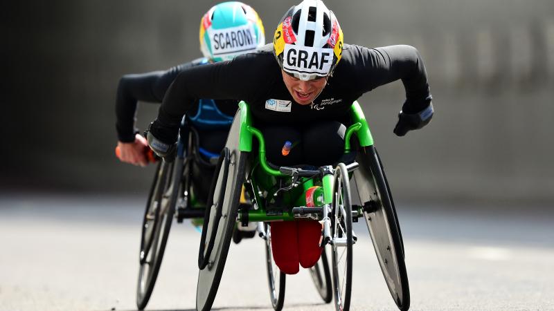 female wheelchair racer Sandra Graf leading another athlete duringa road race