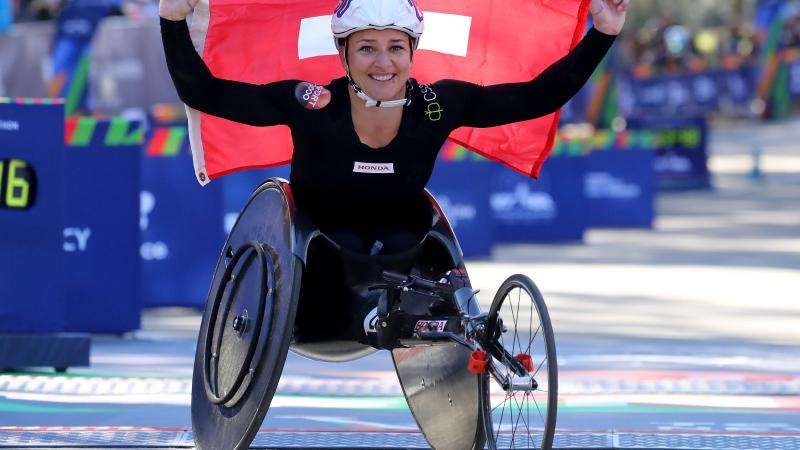 female wheelchair racer Manuela Schaer holding up a Swiss flag