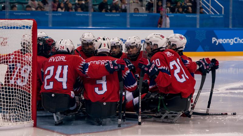 Norwegian Para ice hockey players huddle on an ice rink