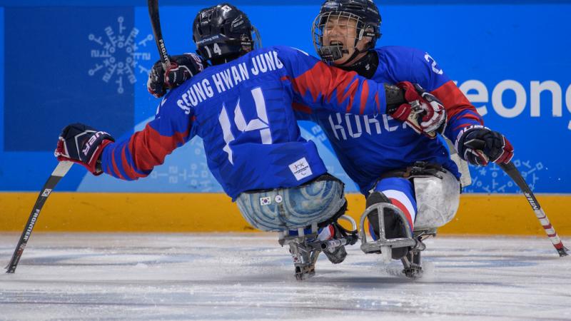 Two Para ice hockey players hug on the ice rink