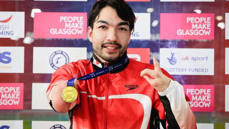 male Para swimmer Takayuki Suzuki holds up his gold medal