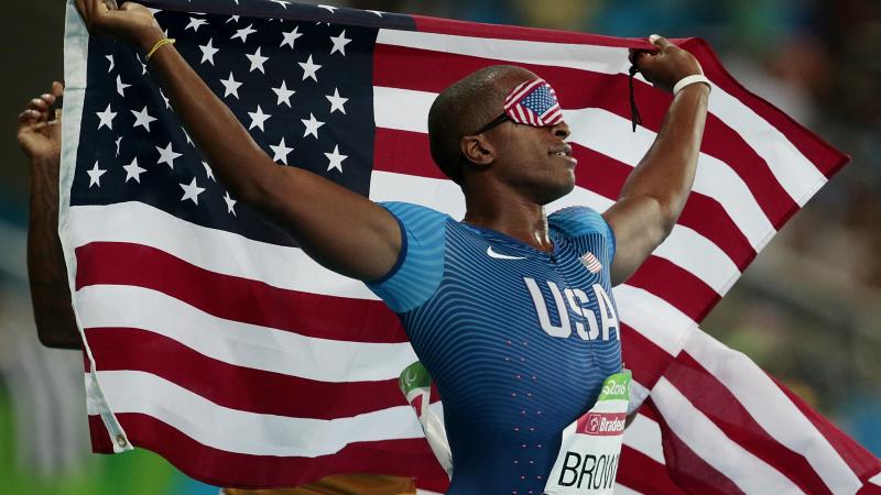 male vision impaired sprinter David Brown holding up the USA flag 