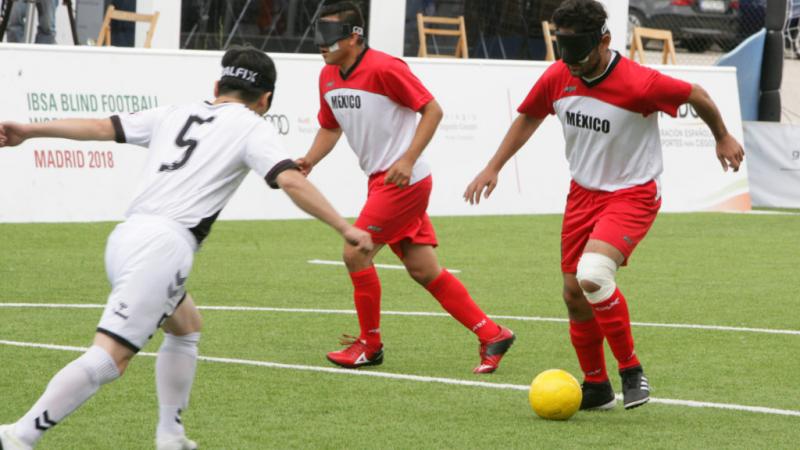 Mexican blind football player Jorge Lanzagorta controls the ball and faces South Korean defender