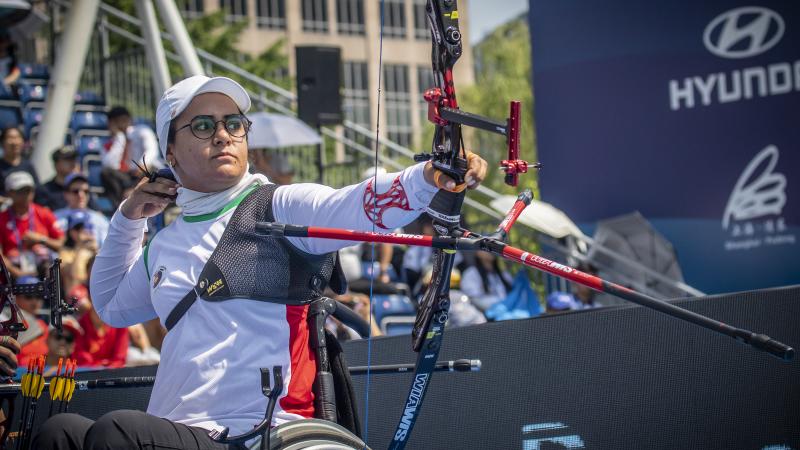 Female Iranian archer in a wheelchair looks on as she releases her arrow