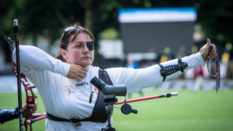 Polish woman with eye patch looks on after shooting her arrow