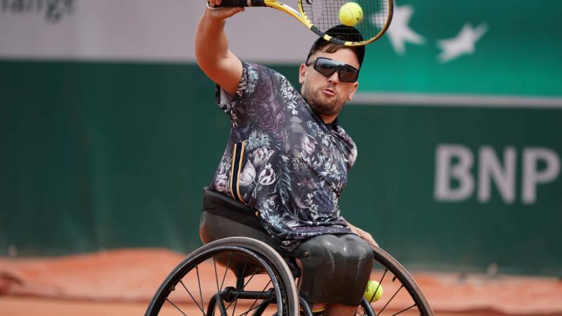 male wheelchair tennis player Dylan Alcott hits a backhand on a clay court