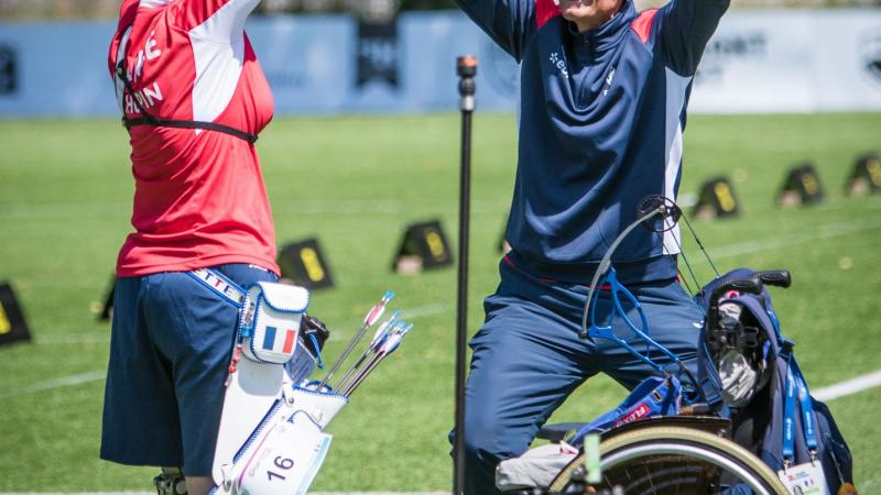 female Para archer Julie Chupin raises her arms in celebration with her coach