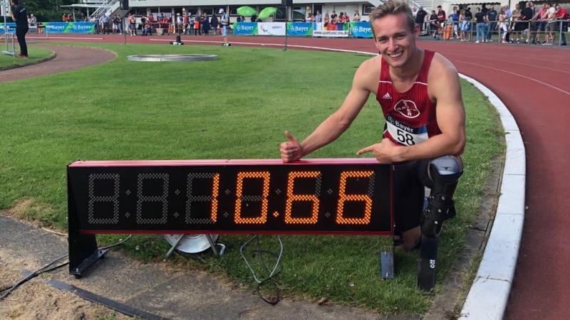German male sprinter poses next to a clock that says 10.66
