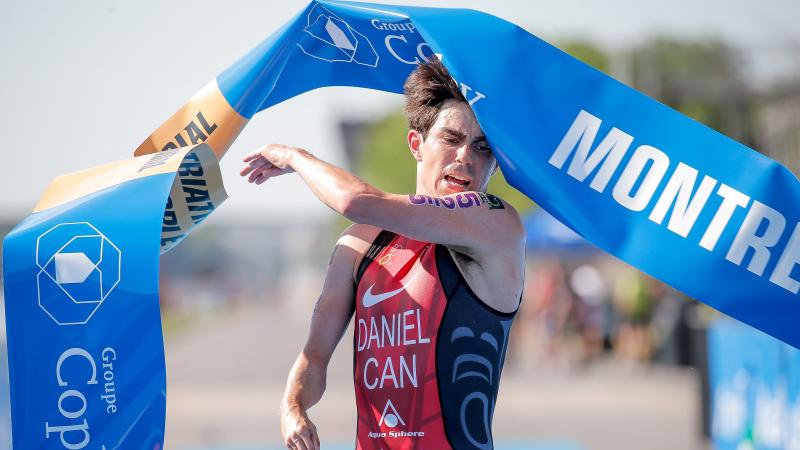 Canadian male triathlete with right arm impairment hits the finish line tape in celebration