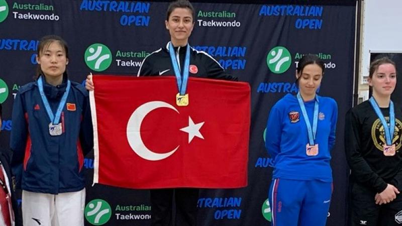 Woman taekwondo fighter on the podium holding the Turkey flag