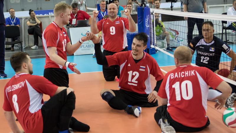 Russian men's sitting volleyball players celebrate on the court after scoring a point