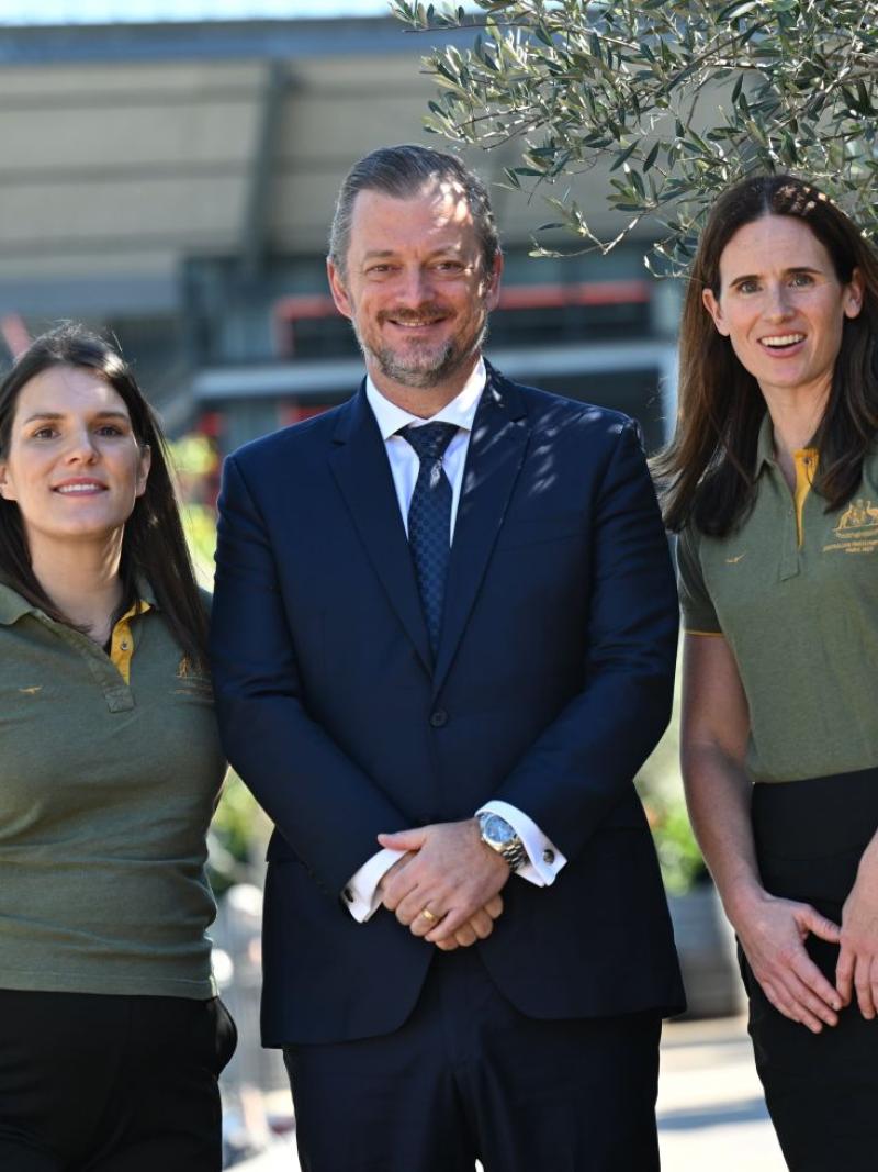 IPC President Andrew Parsons and two female Paralympians wearing Australia's green polo shirt are posing for a photo