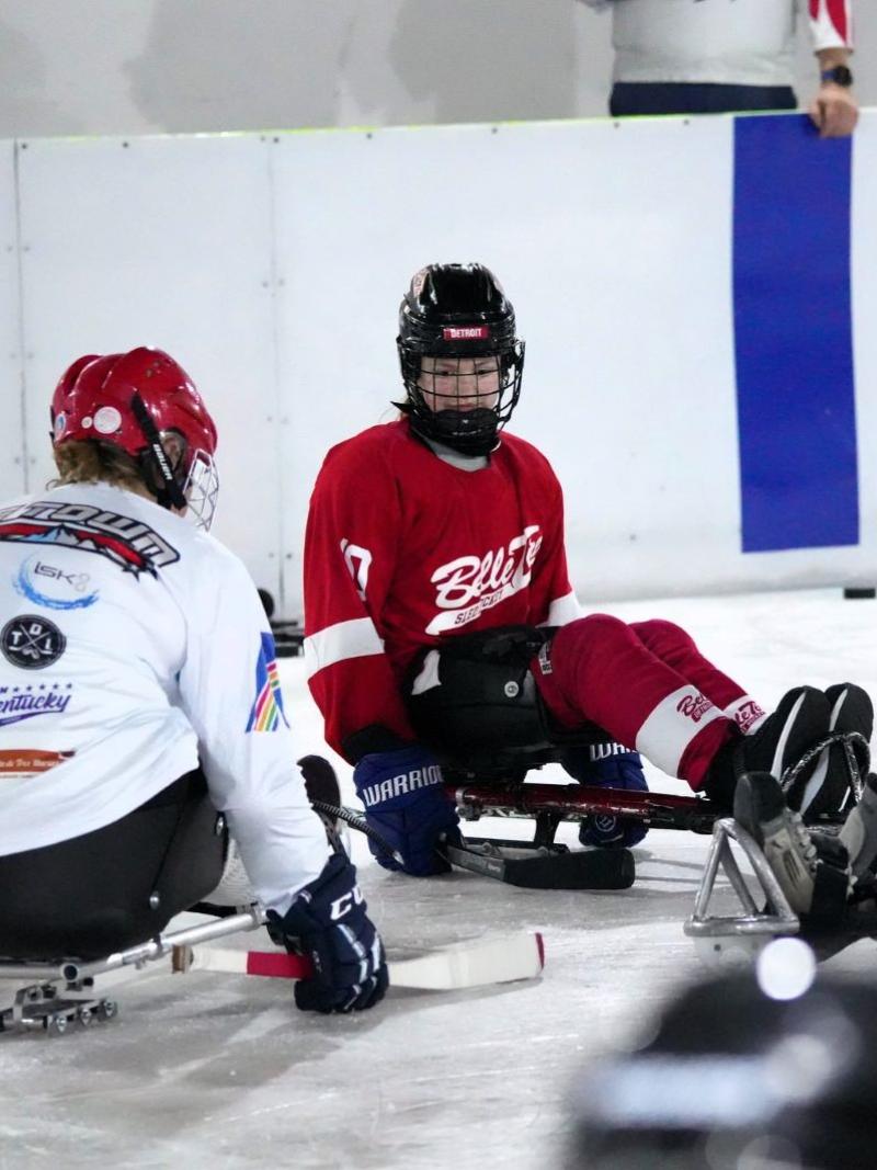 Three women on sledges in an ice rink