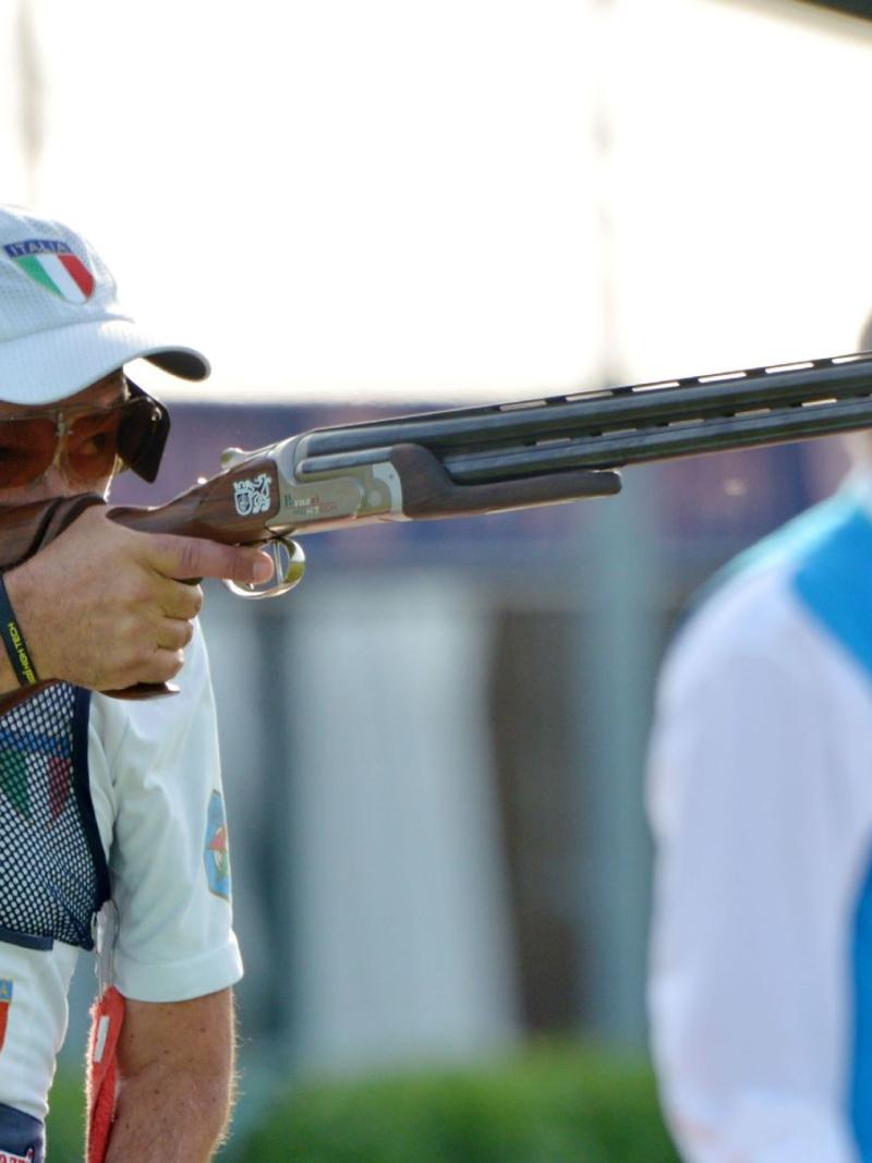 A male trap shooter observed by an official during competition