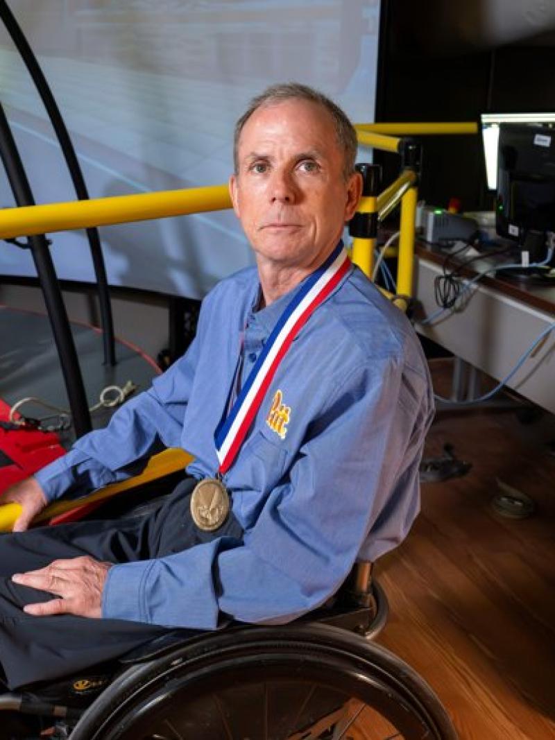 Rory Cooper sitting in a wheelchair with a medal around his neck