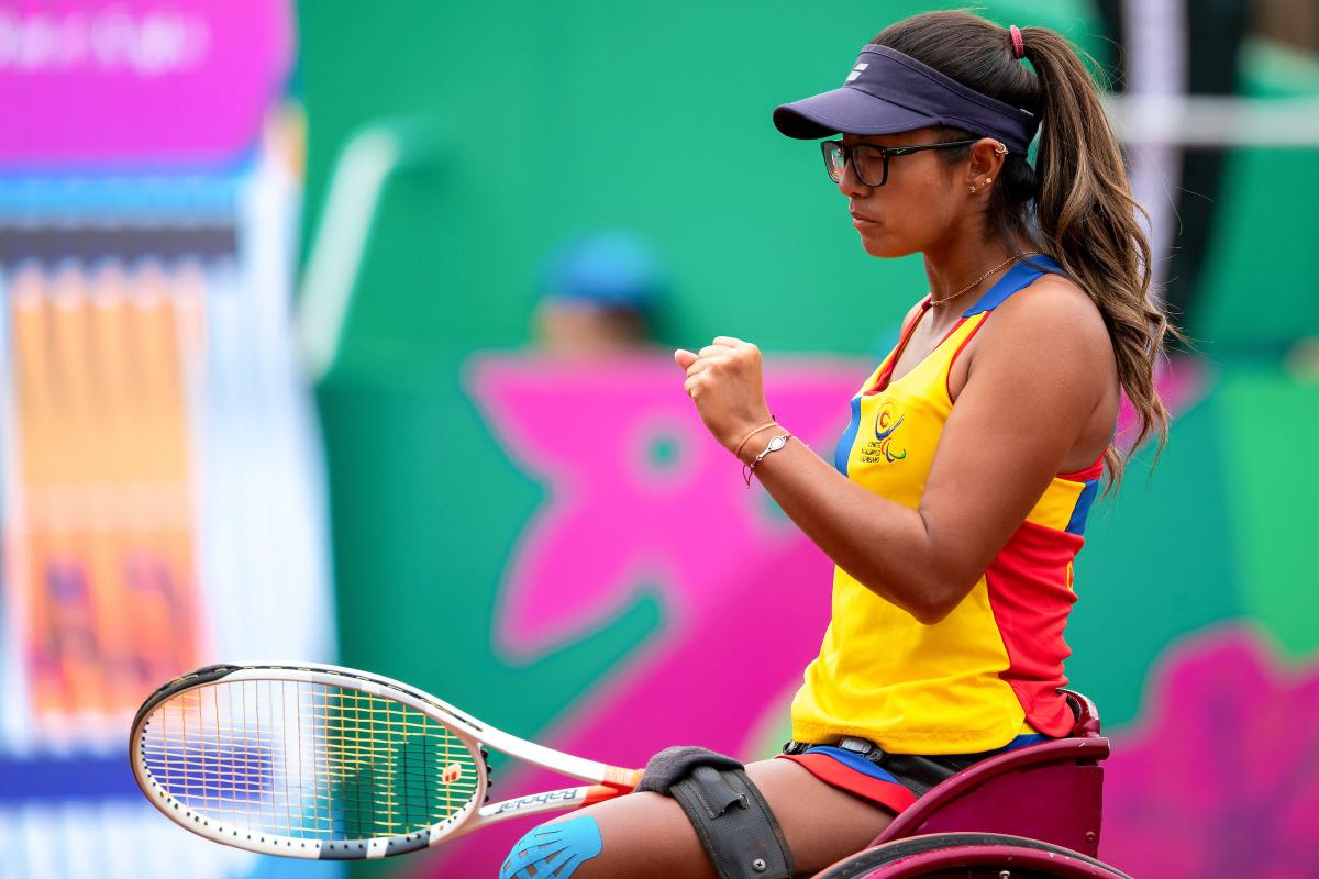 a female wheelchair tennis player clenches her fist on the court
