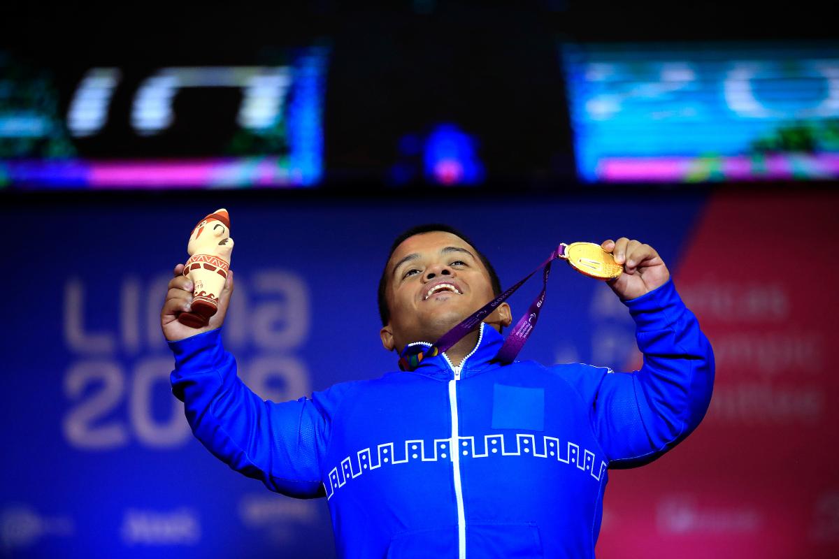 a male powerlifter holds up his gold medal
