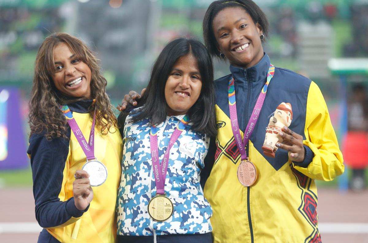three female Para athletes with their medals on the podium