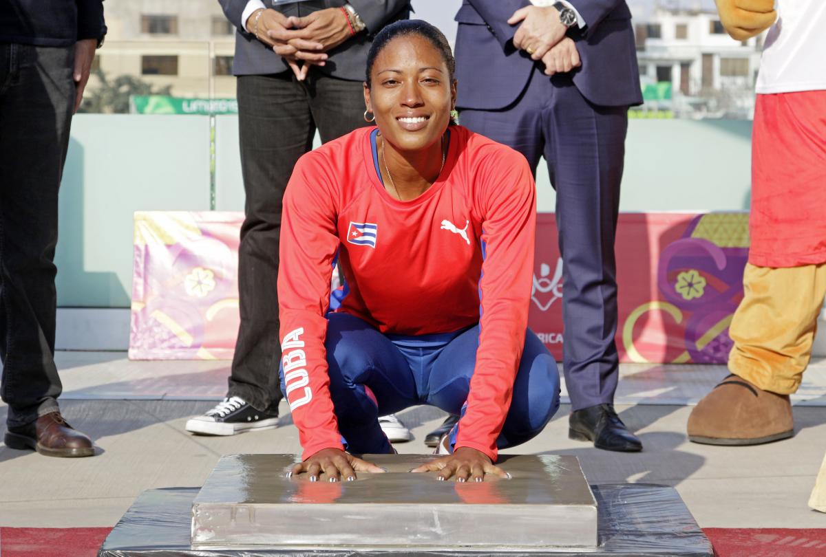 a female Para athlete places her hands in cement to leave prints