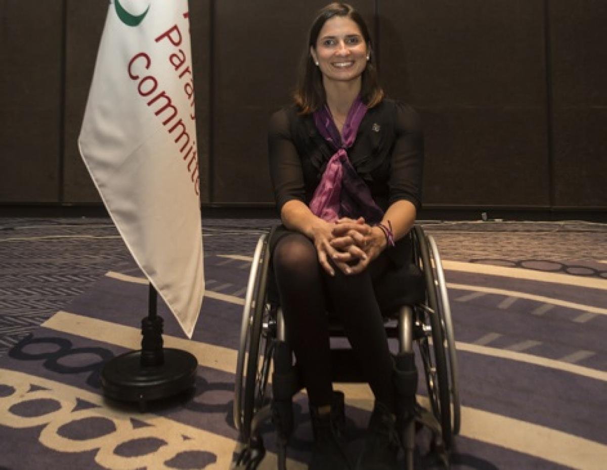 a female wheelchair athlete next to a flag