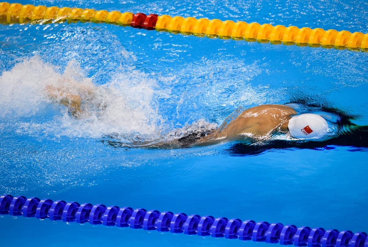 a male Para swimmer with no arms does breaststroke in the water