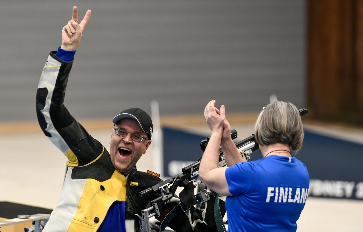 A male shooter celebrating together with a woman with a shirt written Finland