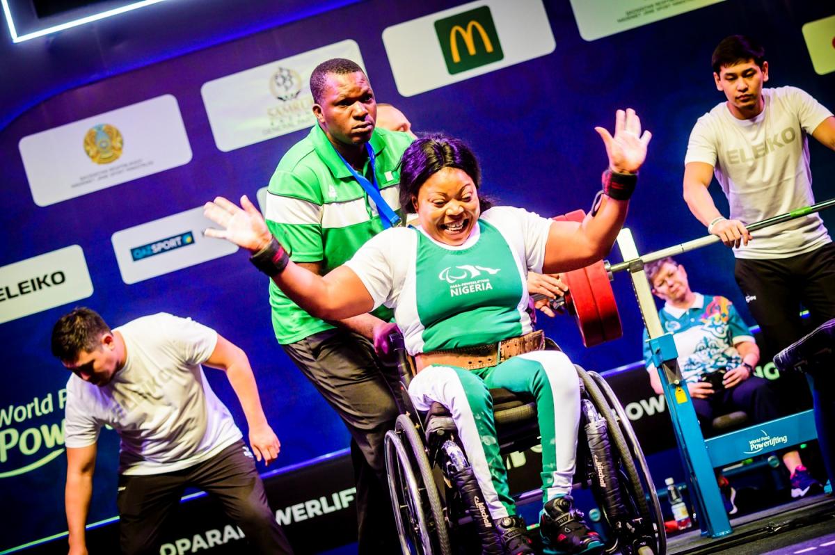 A woman in a wheelchair celebrating with a man standing behind her during a Para powerlifting competition
