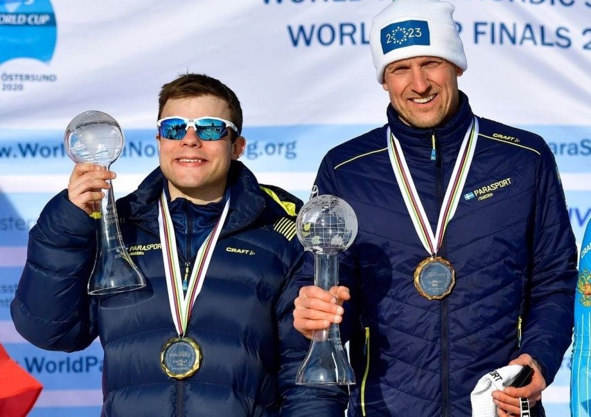 Two men holding with a medal showing their Crystal Globe trophy
