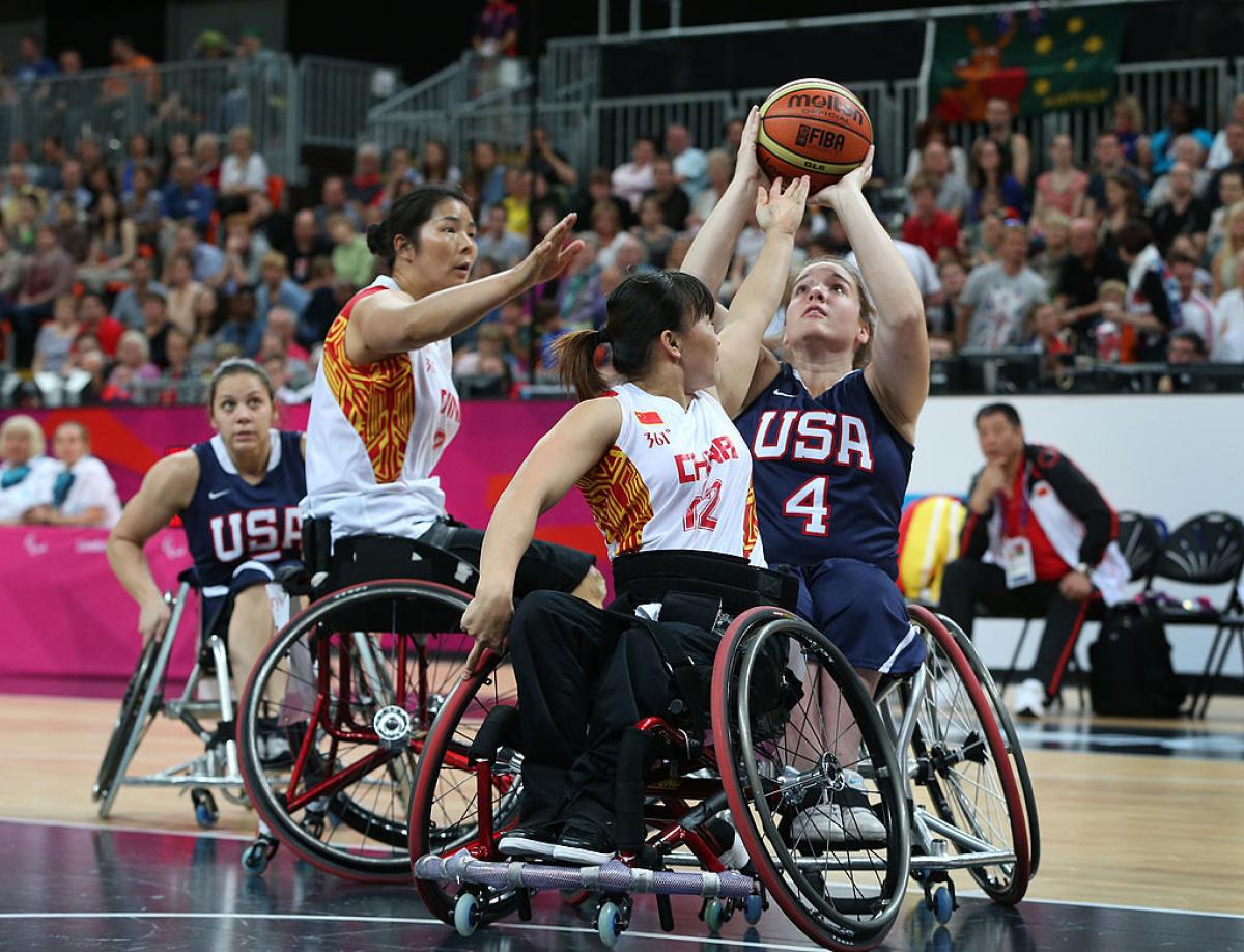 US female wheelchair basketball player shoots the ball while being double teamed