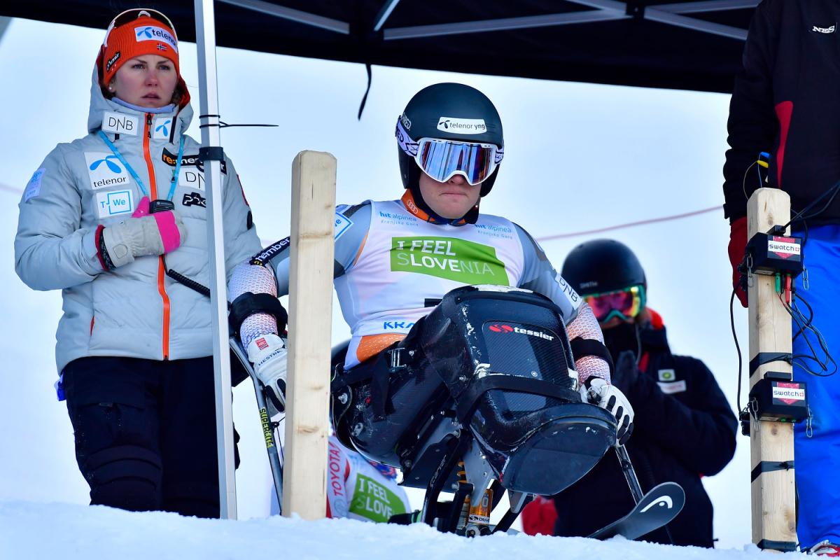 A woman observing a sit-skier at the starting gate