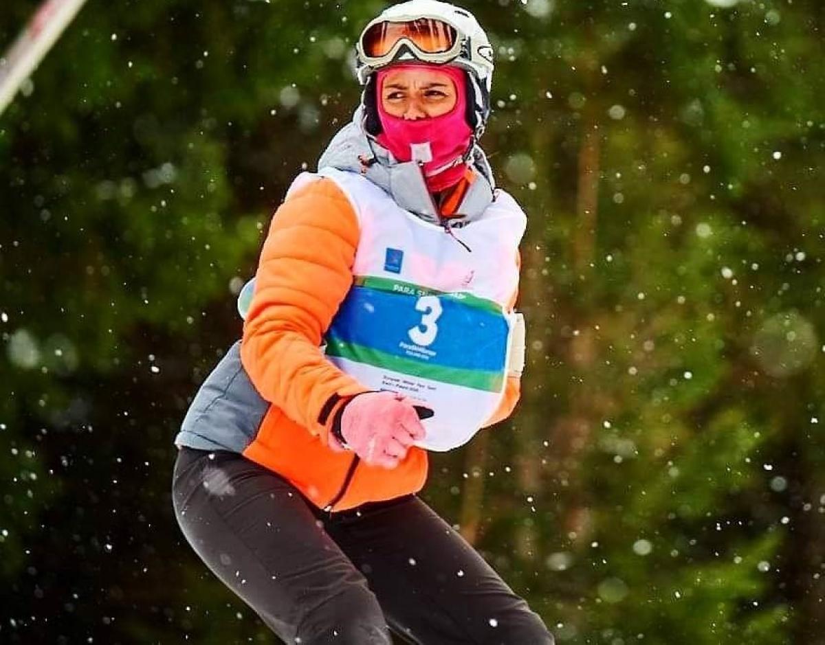 A female Para snowboarder riding with one arm